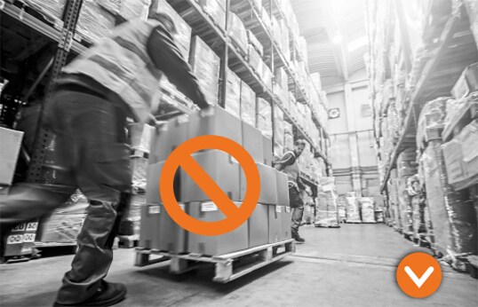 Two adults wheeling a pallet of boxes through a warehouse